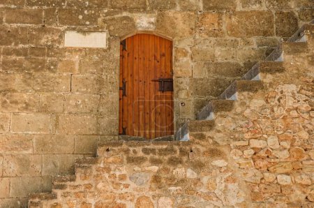 Téléchargez les photos : Une vue des escaliers devant une vieille porte en bois dans un mur de pierre dans la ville pittoresque de Denia, Espagne - en image libre de droit
