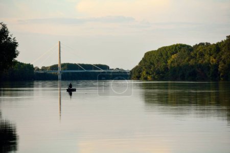 Foto de Una hermosa vista de un pescador en un río Danubio con una hermosa vista del puente Andreas Maurer - Imagen libre de derechos