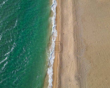 Foto de Una vista aérea de las olas salpicantes del mar en la playa de arena - Imagen libre de derechos