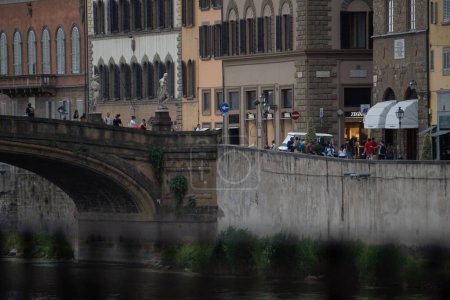 Foto de La gente caminando sobre un puente sobre el río rodeado de hermosos edificios en Florencia Italia - Imagen libre de derechos