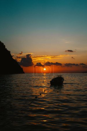 Foto de Un disparo vertical de un barco en la orilla al atardecer con un cielo naranja nublado en el fondo - Imagen libre de derechos