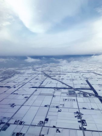 Foto de Una toma aérea de un amplio campo cubierto de nieve en un frío día nublado de invierno - Imagen libre de derechos