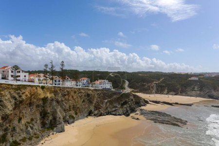 Téléchargez les photos : Une vue aérienne d'une plage avec des maisons résidentielles sur la colline en fond de ciel bleu - en image libre de droit