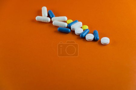 Photo for Stacked pills on orange color background. Medical supplies. - Royalty Free Image