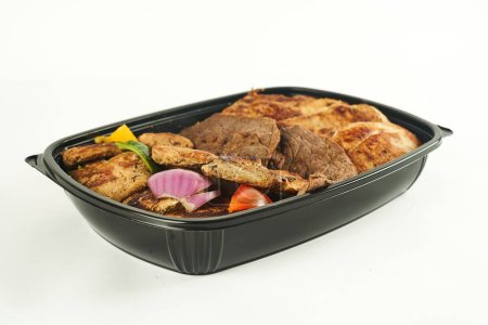 Téléchargez les photos : Gros plan de viande grillée dans un récipient en plastique noir sur fond blanc - en image libre de droit