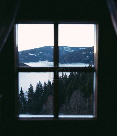 Foto de Una ventana cerrada con vistas a un lago y los árboles y montañas circundantes. - Imagen libre de derechos