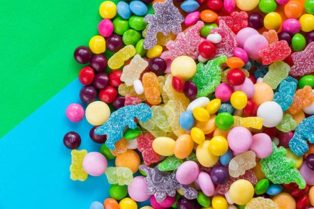 Photo for A horizontal shot of lots of colorful small round candies and jelly together on a blue and green background - Royalty Free Image