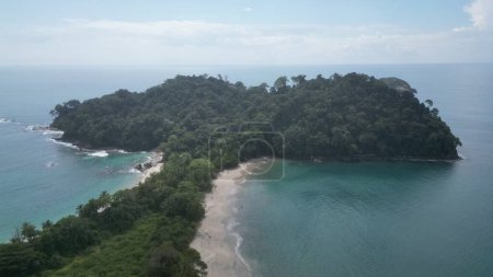 Foto de Un disparo de dron de una isla cubierta de vegetación bajo el cielo azul nublado - Imagen libre de derechos
