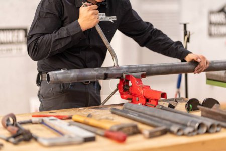 Téléchargez les photos : Gros plan d'une personne travaillant avec des tuyaux métalliques dans un atelier - en image libre de droit