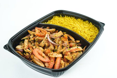 Foto de Un primer plano de carne y verduras a la parrilla y arroz en un recipiente de plástico negro sobre un fondo blanco - Imagen libre de derechos