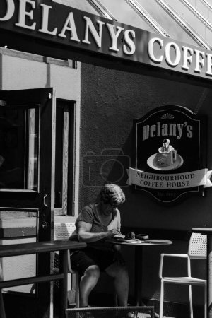 Téléchargez les photos : Échelle de gris verticale d'une femme assise dans un café à Vancouver, Canada - en image libre de droit