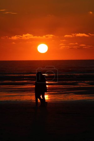 Téléchargez les photos : Un plan vertical d'un coucher de soleil fantastique avec un couple marchant sur la plage à Hardelot, France - en image libre de droit