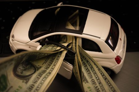 Téléchargez les photos : Une voiture miniature remplie de billets de banque représentant les frais de voiture - en image libre de droit