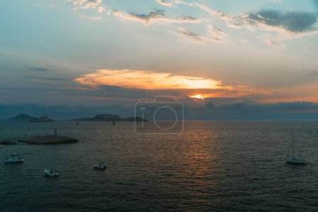 Téléchargez les photos : Une vue panoramique des bateaux sur la mer tranquille lors d'un coucher de soleil envoûtant à Marseille, France - en image libre de droit