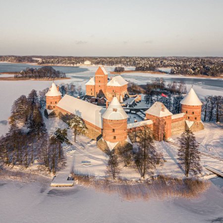 An aerial shot of the medieval Trakai Island Castle on a snowy winter day surrounded by the frozen lake