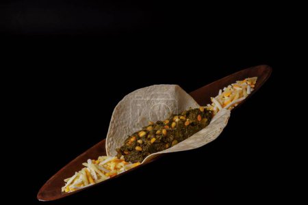 Téléchargez les photos : Taco with spinach and pine nuts and various types of cheeses as garnish and black background - en image libre de droit
