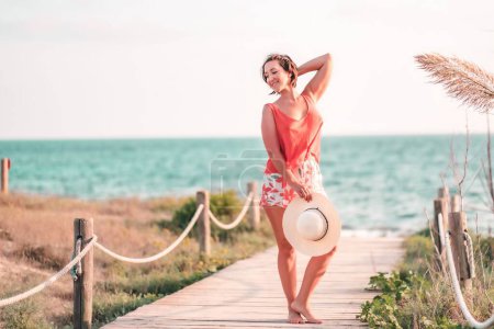 Foto de Una alegre hembra descalza en un muelle de madera sosteniendo peras divirtiéndose en unas vacaciones - Imagen libre de derechos