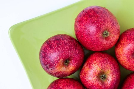 Téléchargez les photos : Une vue de dessus des pommes rouges des espèces pero bravo esmolfe lavées à l'eau douce sur une assiette verte - en image libre de droit