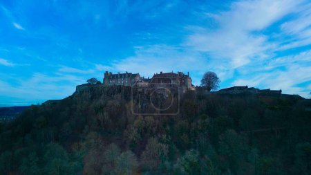 Foto de Una imagen de un castillo de Stirling en la parte superior del bosque bajo el horizonte azul - Imagen libre de derechos