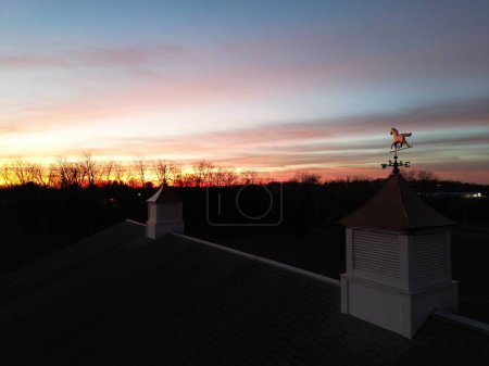 Photo for The horse weathervane on the cupola and the silhouette of trees against the orange-red sky at the sunset - Royalty Free Image