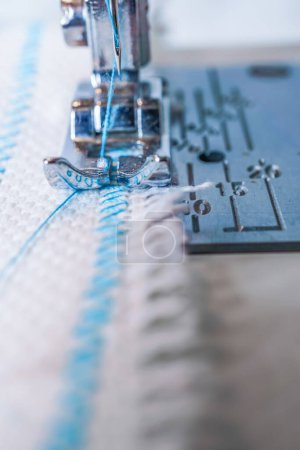 Photo for Close-up of sewing machine needle with blue thread sewing on a white fabric - Royalty Free Image