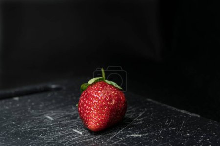 Photo for A closeup shot of a fresh strawberry on the black shelf - Royalty Free Image