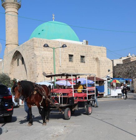 Téléchargez les photos : Plan vertical d'un cheval avec une calèche sur la place devant la mosquée Sinan Basha à Acre, en Israël - en image libre de droit