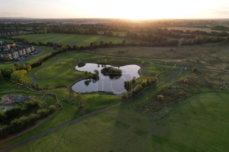 Téléchargez les photos : Une vue aérienne d'un lac dans le champ vert à un coucher de soleil calme - en image libre de droit