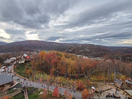 Téléchargez les photos : Vue aérienne de personnes marchant sur une route entre quartier résidentiel et montagnes - en image libre de droit
