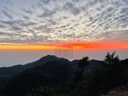 Téléchargez les photos : Une vue paysage des nuages sur les collines et les arbres au coucher du soleil - en image libre de droit