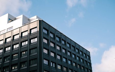 Téléchargez les photos : Un bâtiment carré moderne sur fond bleu ciel nuageux avec des murs sombres - en image libre de droit