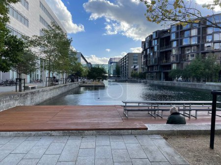 Téléchargez les photos : Une personne assise sur un banc en face d'un canal à Copenhague, Danemark - en image libre de droit