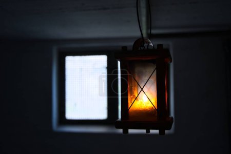 Photo for A closeup of a lit retro lantern, lamp hanging in front of a window - Royalty Free Image