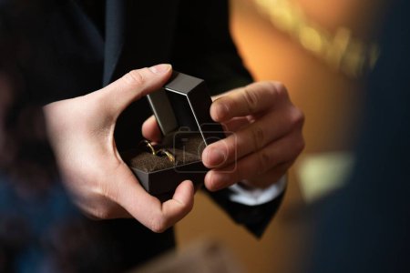 Foto de Un plano superficial de las manos del hombre sosteniendo anillos de boda en una caja negra - Imagen libre de derechos