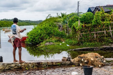 Téléchargez les photos : Pêcheur jetant un appât pour attraper du poisson sur le bord de la rivière Jaguaripe dans la ville d'Aratuipe, Bahia. - en image libre de droit