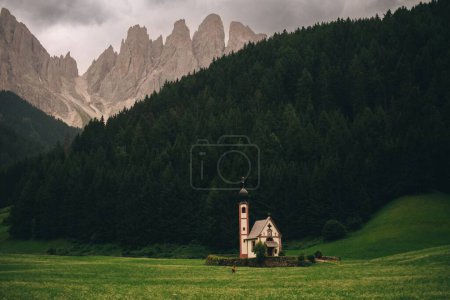 Téléchargez les photos : L'église de Saint-Jean dans le champ vert sur le fond de collines forestières fascinantes, Italie - en image libre de droit
