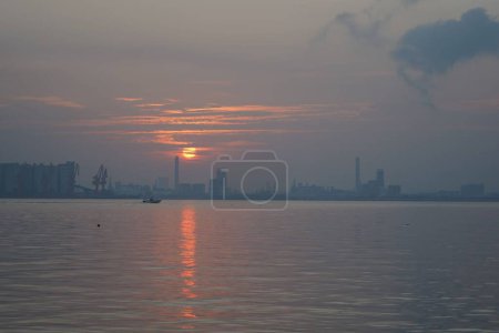 Téléchargez les photos : Scène paisible reflétée sur la surface de l'eau de mer au lever du soleil - en image libre de droit