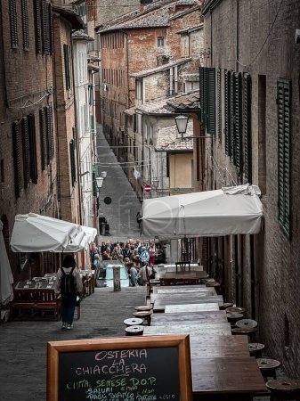 Téléchargez les photos : Une verticale d'une rue italienne étroite avec un groupe de personnes âgées réunies - en image libre de droit