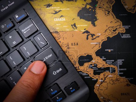Foto de Un primer plano de un dedo presionando "enter" en un teclado negro en la parte superior del mapa de EE.UU. - concepto de negocio - Imagen libre de derechos