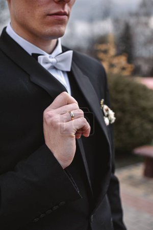 Téléchargez les photos : Un plan vertical du marié tenant son costume noir avec arc de mariage blanc sur un fond flou - en image libre de droit