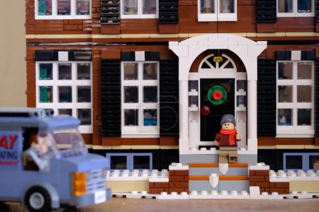 Téléchargez les photos : Une petite figurine lego en attente devant la porte de la maison lego pour la livraison avec une voiture violette - en image libre de droit