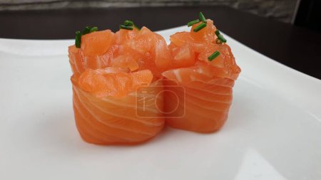 Téléchargez les photos : Un gros plan de rouleaux de saumon dans un restaurant japonais servi sur une assiette blanche - en image libre de droit