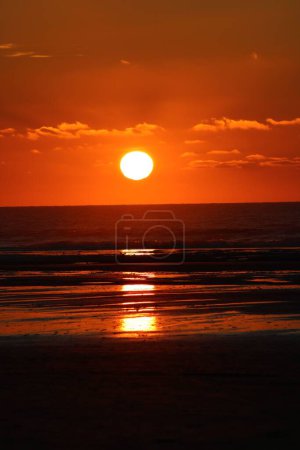 Téléchargez les photos : Un plan vertical d'un coucher de soleil fantastique avec le reflet dans les eaux à Hardelot, France - en image libre de droit