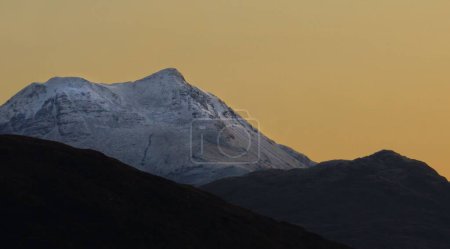 Foto de Un primer plano de una montaña cubierta de nieve sobre un fondo de cielo amarillo - Imagen libre de derechos