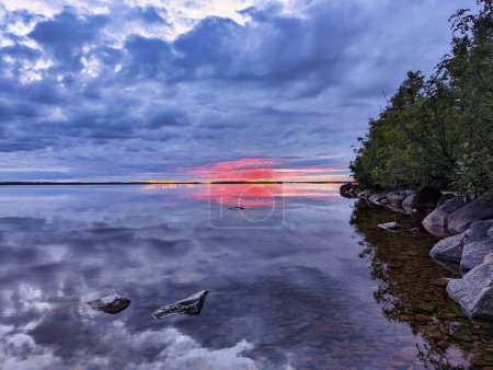 Foto de Un hermoso lago con una costa rocosa contra el cielo del atardecer - Imagen libre de derechos