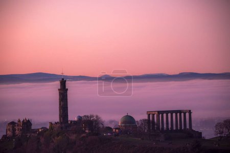 Téléchargez les photos : Une vue panoramique du siège d'Arthur sur Calton Hill couvert de nuages au coucher du soleil rose en Écosse - en image libre de droit