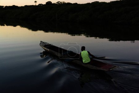 Téléchargez les photos : Un pêcheur pagayant en canot sur la rivière Jaguaripe, ville d'Aratuipe, au coucher du soleil. - en image libre de droit