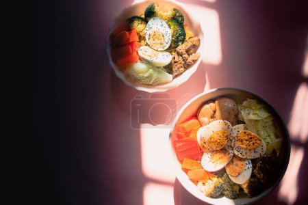 Téléchargez les photos : Vue de dessus de deux bols de repas de céto à haute teneur en protéines faits de carottes cuites à la vapeur, brocoli, chou, oeuf et foie de poulet - en image libre de droit