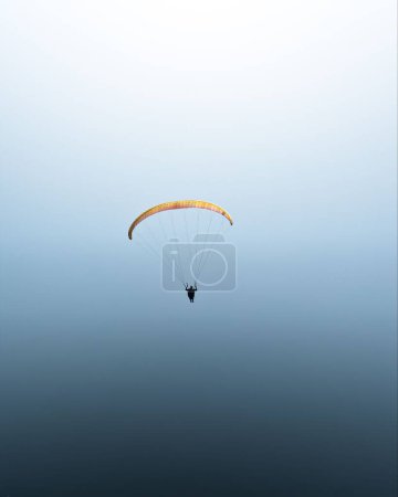 Foto de Una vista impresionante de una persona parapente sobre el mar abierto en un cielo despejado y sin nubes. Ideal para fondos de teléfono - Imagen libre de derechos