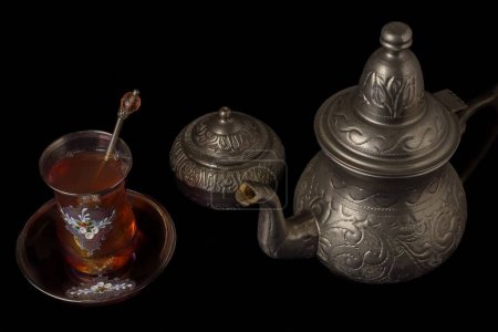 Photo for Tea cup decorated with teapot and metal sugar bowl isolated on black background - Royalty Free Image